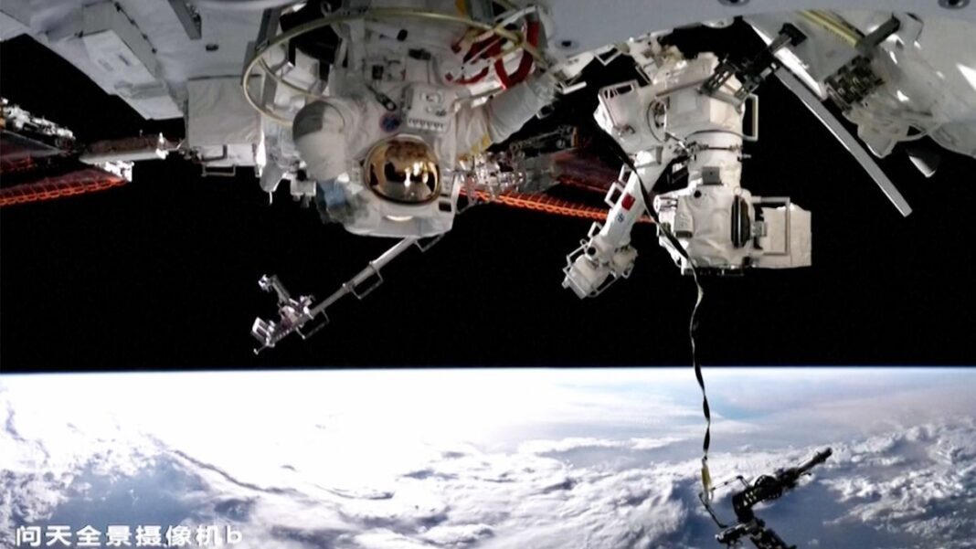 chinese taikonaut upside down during a spacewalk with the earth below