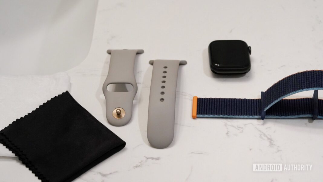 Apple Watch Series 6 and two bands rest on a bathroom counter along with clothes need to clean Apple Watch bands