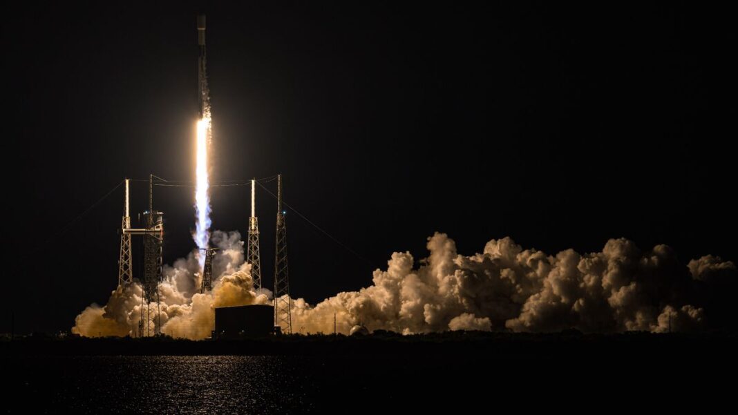 a black-and-white spacex falcon 9 rocket launches into a night sky.
