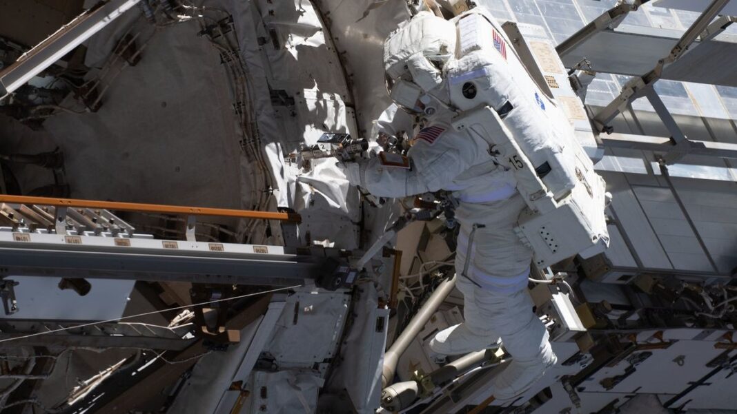 an astronaut in a spacesuit facing the international space station