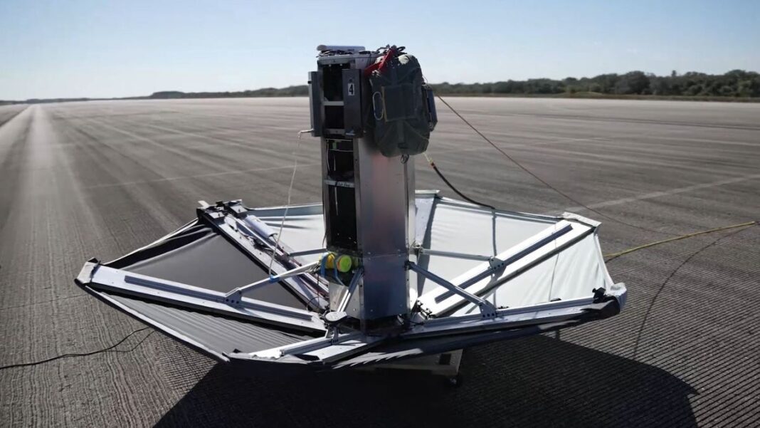 a device that resembles a large upside-down umbrella sits on a black asphalt runway