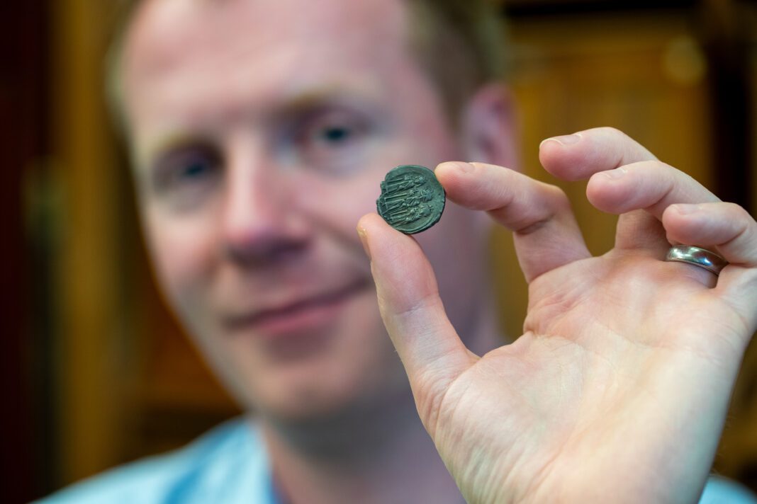 Cambridge University historian Rory Naismith holding Anglo Saxon coin